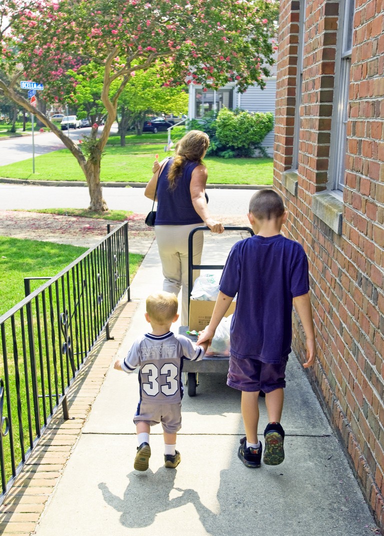 Mother and two sons leave pantry with cart filled with food