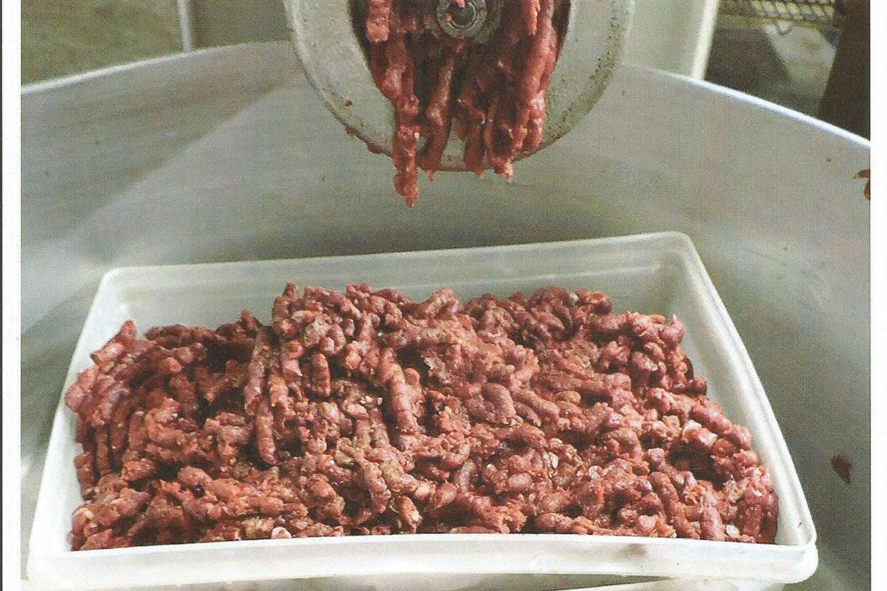 Venison being ground into a bin for packaging